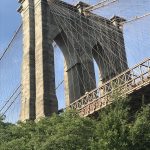 Brooklyn Bridge with trees in the foreground.